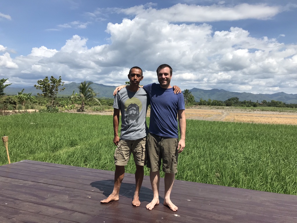 ATWR executive director Andrew Murphy and local liaison Suriya Kalasin standing together on a deck in front of rice fields and mountains in northern Thailand
